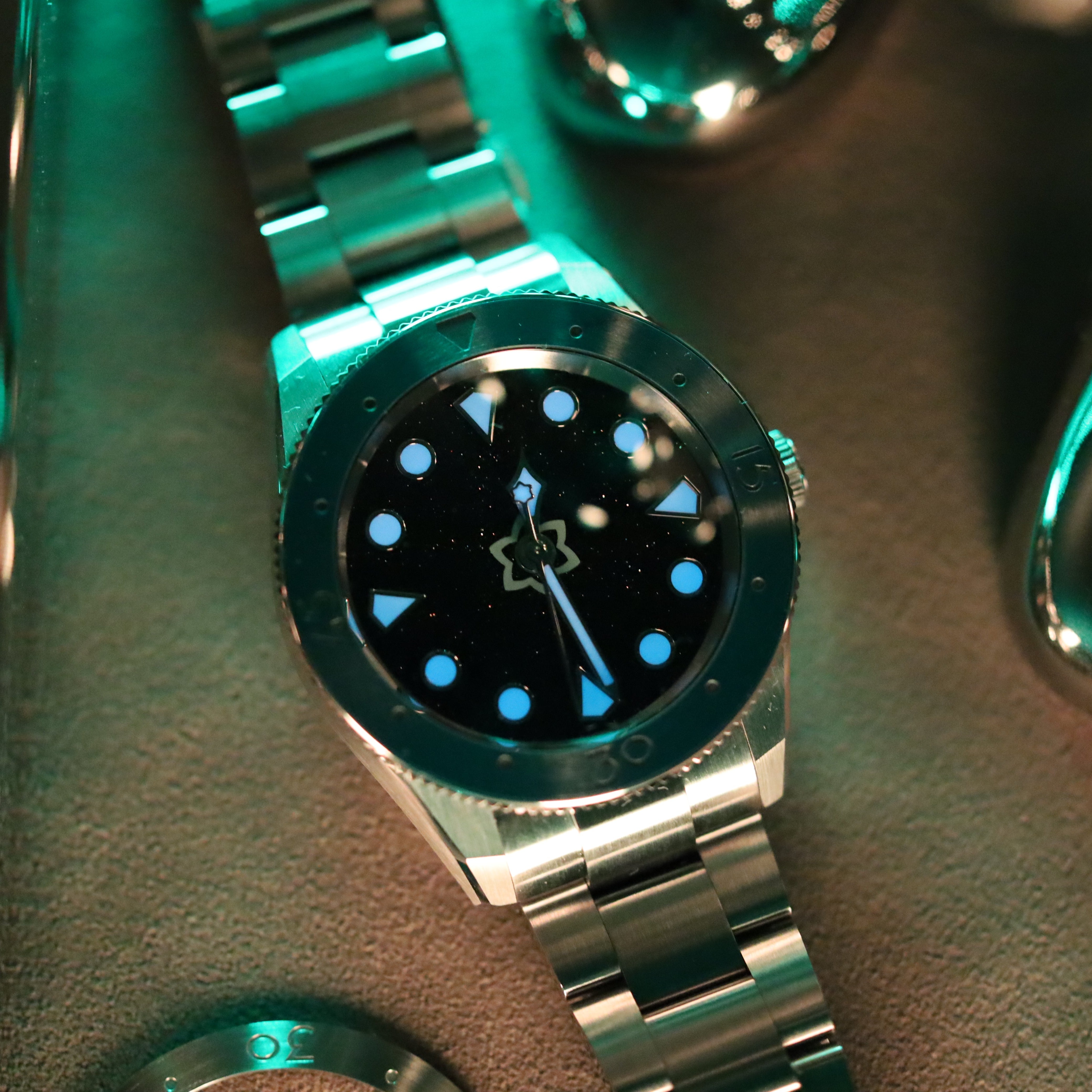 Close-up of a silver watch with a black face on a dark background