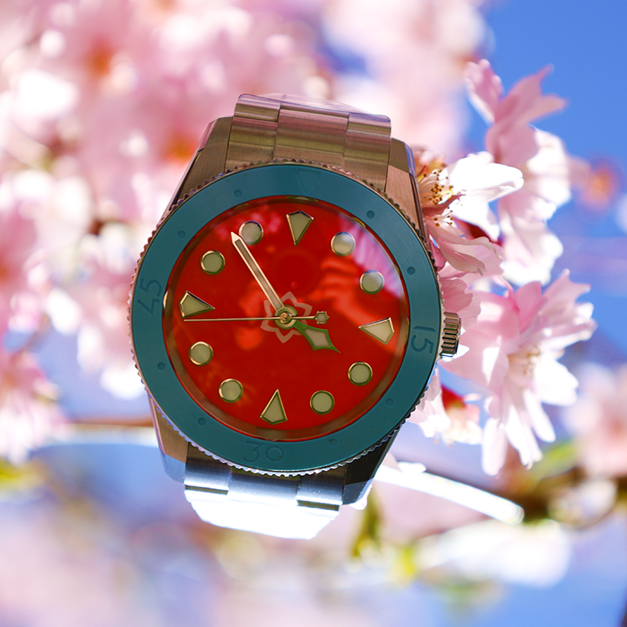 Colorful watch with a red face and blue casing on cherry blossom branches