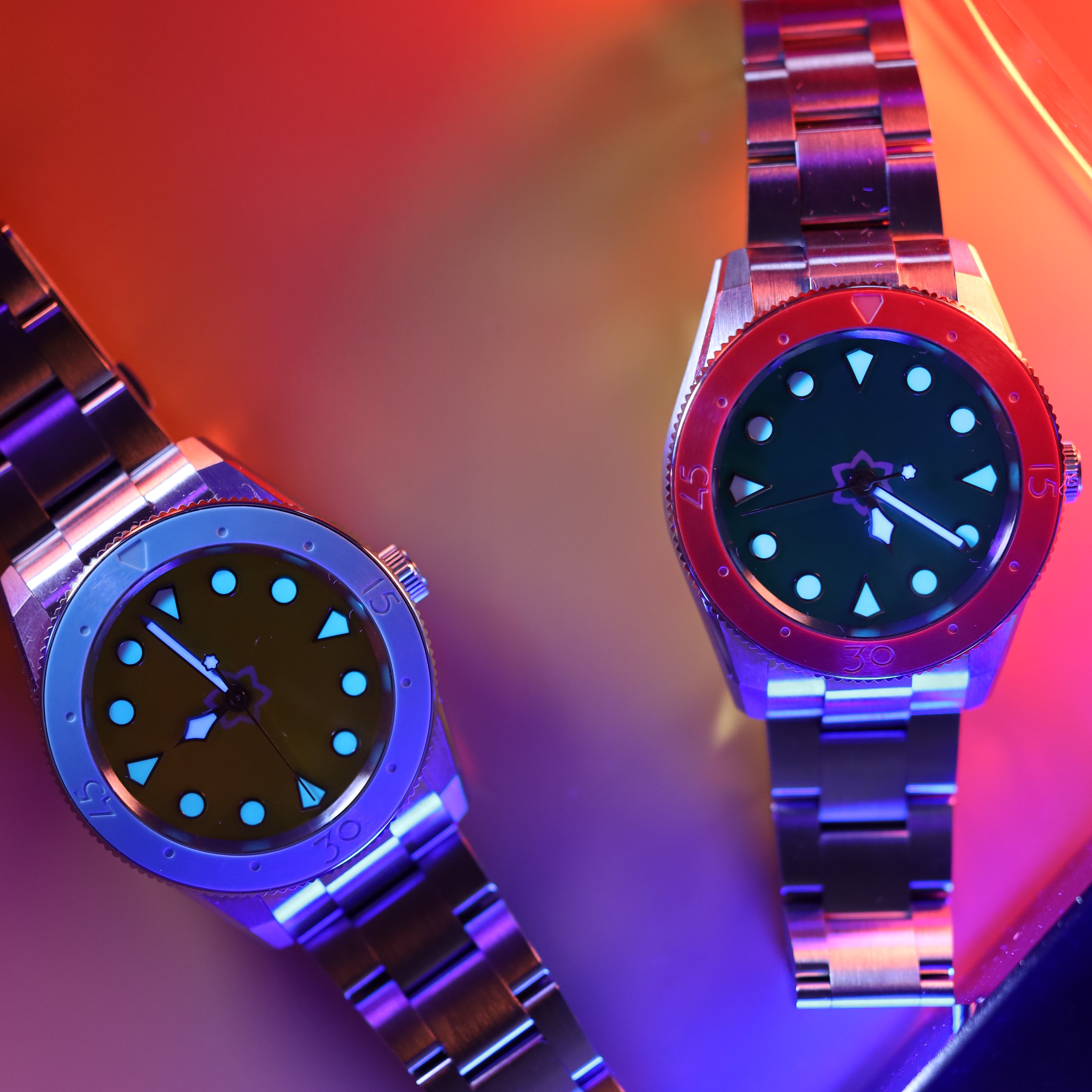 Two watches with metallic bands on a colorful background